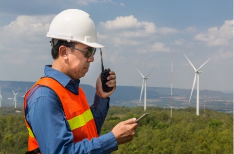 man in hard hat and orange high-vis with portable radio working at wind farm - Scotia Radio Hytera HP5 series